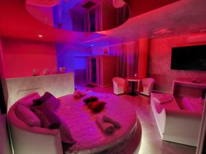2 persone sdraiate su un letto in una stanza con luci rosa di B&B Luxury Room & SPA a Apricena