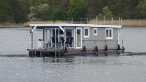 吕贝克Hausboot Janne Lübeck Inclusive Kanu nach Verfügbarkeit SUP und WLAN 50 MBit s Flat的水面上的小房子