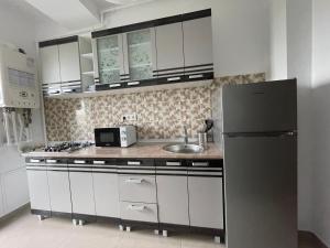 een keuken met witte kasten en een zwarte koelkast bij WOW Park Drumul Taberei apartment in Boekarest