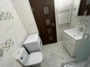 een witte badkamer met een toilet en een wastafel bij WOW Park Drumul Taberei apartment in Boekarest +8 foto's