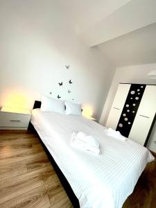 een slaapkamer met een wit bed met zwarte vlinders aan de muur bij WOW Park Drumul Taberei apartment in Boekarest