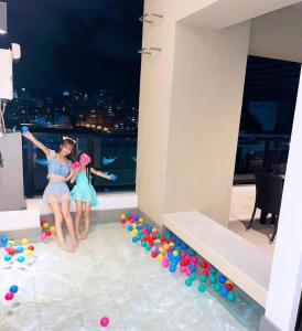 two girls are sitting on a balcony with balls at ゆくれば前島ホテル in Naha