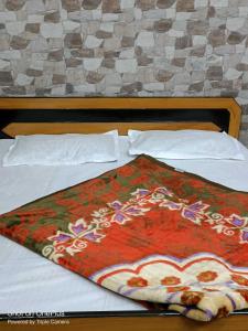 a bed with a colorful blanket on top of it at OYO Home Tawi View Home in Jammu