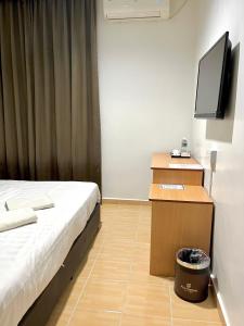 a room with a bed and a desk with a television at Hotel Premier Inn (Prima Square) in Sandakan