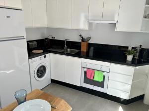 a white kitchen with a sink and a washing machine at Casa mi sùeño azul in Torrox