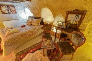 a bedroom with a bed and a desk and a mirror at Cappadocia Alaz Cave Otel in Nevşehir