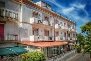 a large white building with balconies on a street at Hotel Pineta in San Menaio