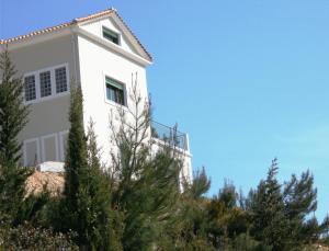 a white house on top of a hill with trees at Porto Katsiki Blu in Athani