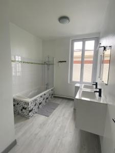 un bagno bianco con vasca e lavandino di Le Duplex a Louviers