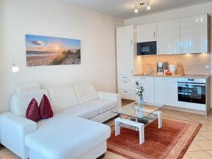 ein Wohnzimmer mit einem weißen Sofa und einem Tisch in der Unterkunft Villa Jasmin App. 1 in Heringsdorf