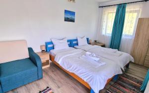 sypialnia z 2 łóżkami i niebieskim krzesłem w obiekcie Splendoarea Deltei w mieście Maliuc