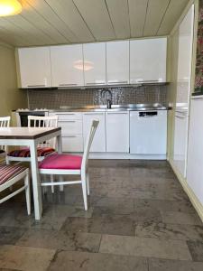 - une cuisine avec des placards blancs, une table et des chaises dans l'établissement Längtan Marielund, à Uppsala