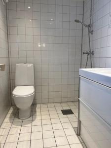 a white bathroom with a toilet and a sink at Längtan Marielund in Uppsala