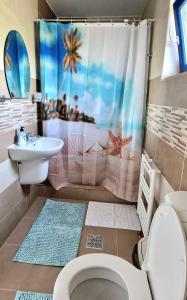 a bathroom with a shower curtain with a toilet and a sink at Splendoarea Deltei in Maliuc