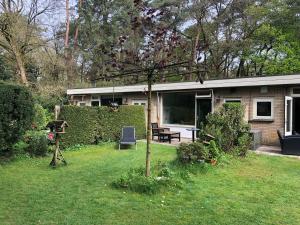 ein Haus mit einem Hof mit einem Zaun und einer Bank in der Unterkunft Veluwe Nature Home - 2 persons in Otterlo