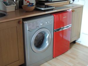 a washing machine in a kitchen with a red dishwasher at Burns Cottage in Dalleagles