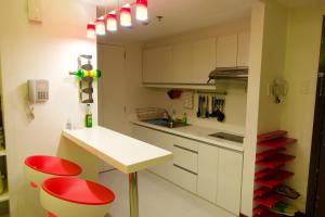 uma pequena cozinha com bancos vermelhos e um balcão branco em Luxury Condo at Forbeswood Parklane The Fort BGC em Manila