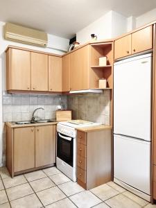 a kitchen with wooden cabinets and a white refrigerator at Derveni Seaside Apartments "Groundfloor" in Derveni
