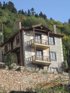 duży kamienny budynek z balkonem na wzgórzu w obiekcie Villa Korfes-Κορφές Τριώροφη Βίλα για Οικογένειες και Παρέες w mieście Karpenision