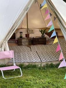 Tienda de campaña con cama y silla en el césped en Willow glamping en Norwich