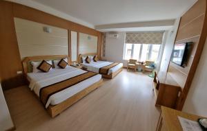 a hotel room with two beds and a flat screen tv at Ánh Dương Hotel Hải Phòng in An Khê