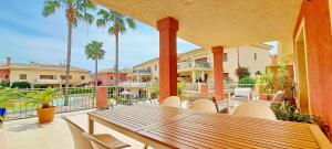 een houten tafel en stoelen op een patio met palmbomen bij Jardines de Montemar IV in Benissa