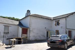 une voiture garée devant un bâtiment blanc dans l'établissement GITE DE LA COMBE BASSE, à Le Masnau-Massuguiès