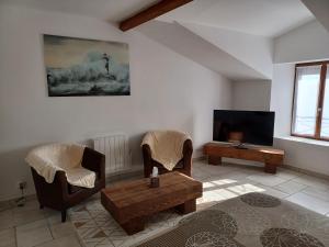 sala de estar con 2 sillas y TV en La Grange 3 étoiles - Maison d'hôte à 10 min des plages, en Thairé