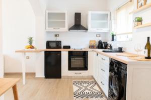 a kitchen with white cabinets and a black dishwasher at White Dream House in Kos
