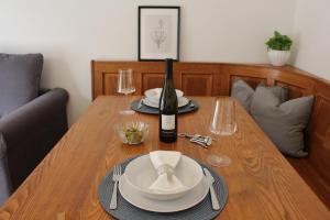un tavolo in legno con una bottiglia di vino e bicchieri di Elina Apartment a Merano
