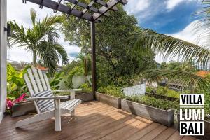 un patio con una silla, una sombrilla y palmeras en Lumi Villa en Uluwatu