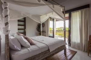 1 dormitorio con cama con dosel y balcón en Lumi Villa, en Uluwatu