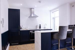 a kitchen with dark blue cabinets and black stools at Designer Cardiff Apartments in Cardiff