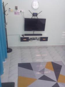 Adilah Homestay B في باسير بوته: غرفة معيشة مع تلفزيون بشاشة مسطحة على جدار