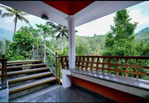 balcón con escaleras y vistas al bosque en MUNNAR FALCUNS INN HOMESTAY en Munnar