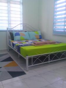 1 dormitorio con 1 cama con sábanas y almohadas verdes en Adilah Homestay B en Pasir Puteh
