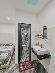 a bathroom with a sink and a toilet and a bed at Nhà nghỉ IZUMI Phương Trang in Vung Tau
