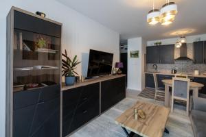 een keuken met zwarte kasten en een tafel in een kamer bij Red Bridge Apartament in Dziwnów