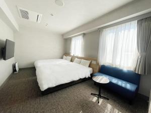 松江市にある松江ニューアーバンホテルのベッドルーム(大型ベッド1台、青いソファ付)