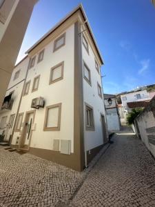 a white building with a door on a street at Ascensor à Vista in Nazaré