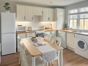 uma cozinha com electrodomésticos brancos e uma mesa com cadeiras em Denburn Cottage em Colinsburgh
