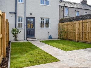 una casa con una valla de madera y un patio en Denburn Cottage, en Colinsburgh