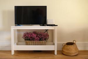 een tv op een witte tafel met bloemen bij Troia Beach and Nature - Apartment in Troia