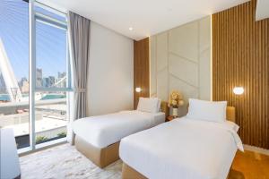 two beds in a hotel room with a large window at Livbnb - Alluring 3BR+1 w/Sea & Ain Dubai View in Dubai