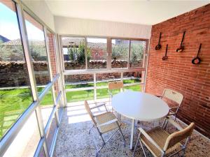 a room with a white table and chairs and windows at Casa Rural EL HUERTO con Jardín in Lumbrales