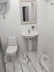 a white bathroom with a sink and a toilet at Mirage in Chernivtsi