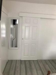 a white room with a door and a mirror at En Suite Double Room in London