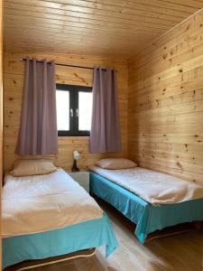Duas camas num quarto com paredes de madeira em Toscana Camp em Pogorzelica