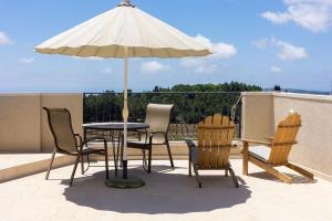 a table with chairs and an umbrella on a patio at ג'וליוס סוויטה in Adamit