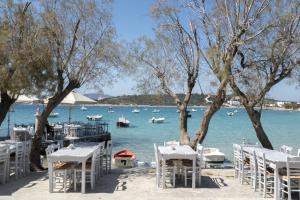 a beach with tables and chairs and boats in the water at Cavos Paros Boho Chic sea-view apartment in Aliki in Aliki
